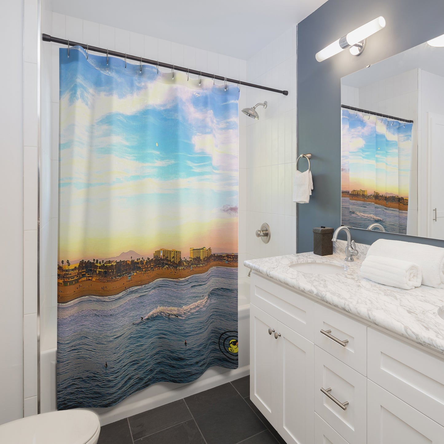 Modern bathroom with a Malibu surf themed shower curtain showcasing ocean waves, pastel sky, and beach skyline.