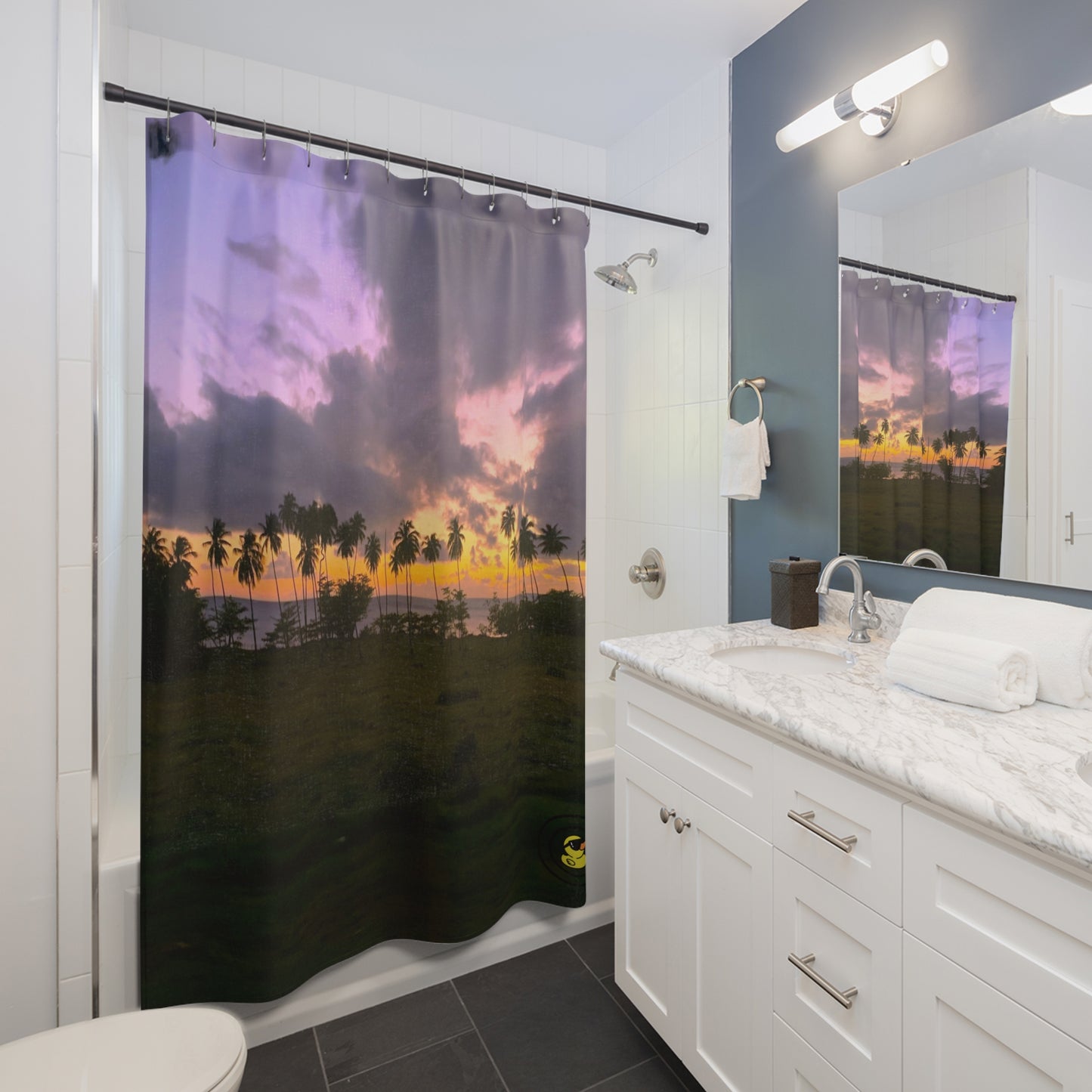 Tropical sunset shower curtain with palm trees and colorful sky in a modern white bathroom with marble vanity.