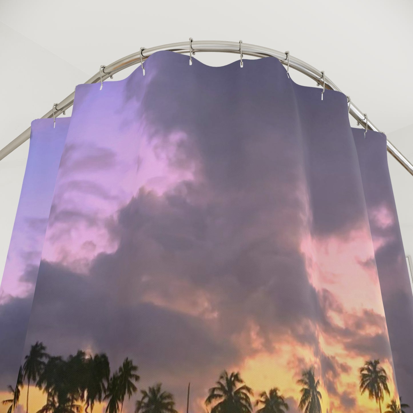 Shower curtain with tropical palm silhouettes under dramatic purple and orange sunset clouds.