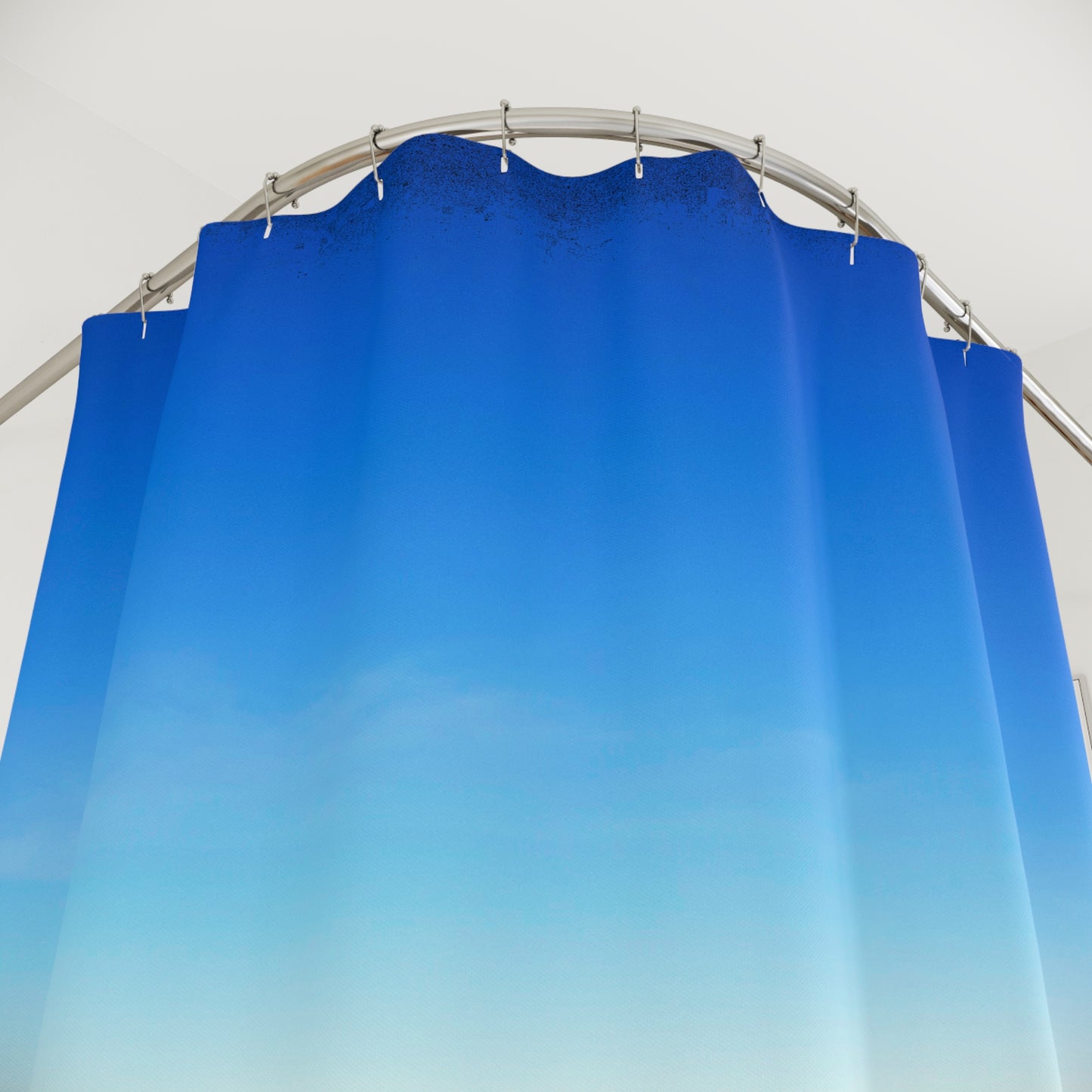 Modern bathroom with blue gradient shower curtain hanging from a curved rod, creating a clean, airy look.