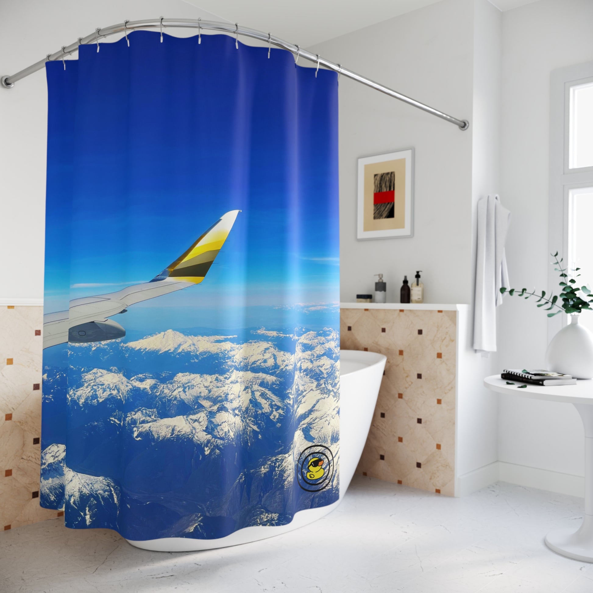 Bathroom with shower curtain showing airplane wing over clouds and snow-capped mountains under clear blue sky.