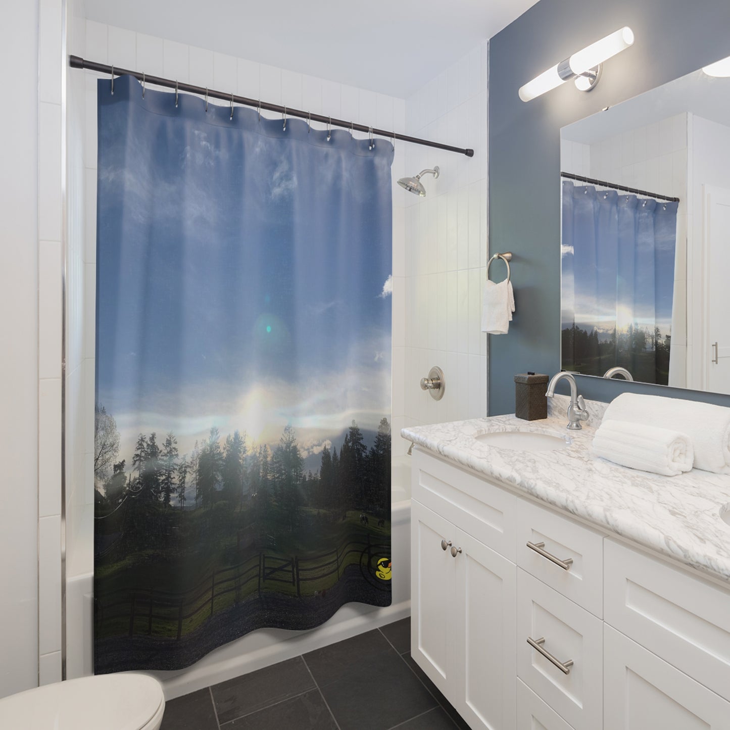 Bathroom with a shower curtain featuring a serene farm sunset. Casting soft light over tree silhouettes and open fields.