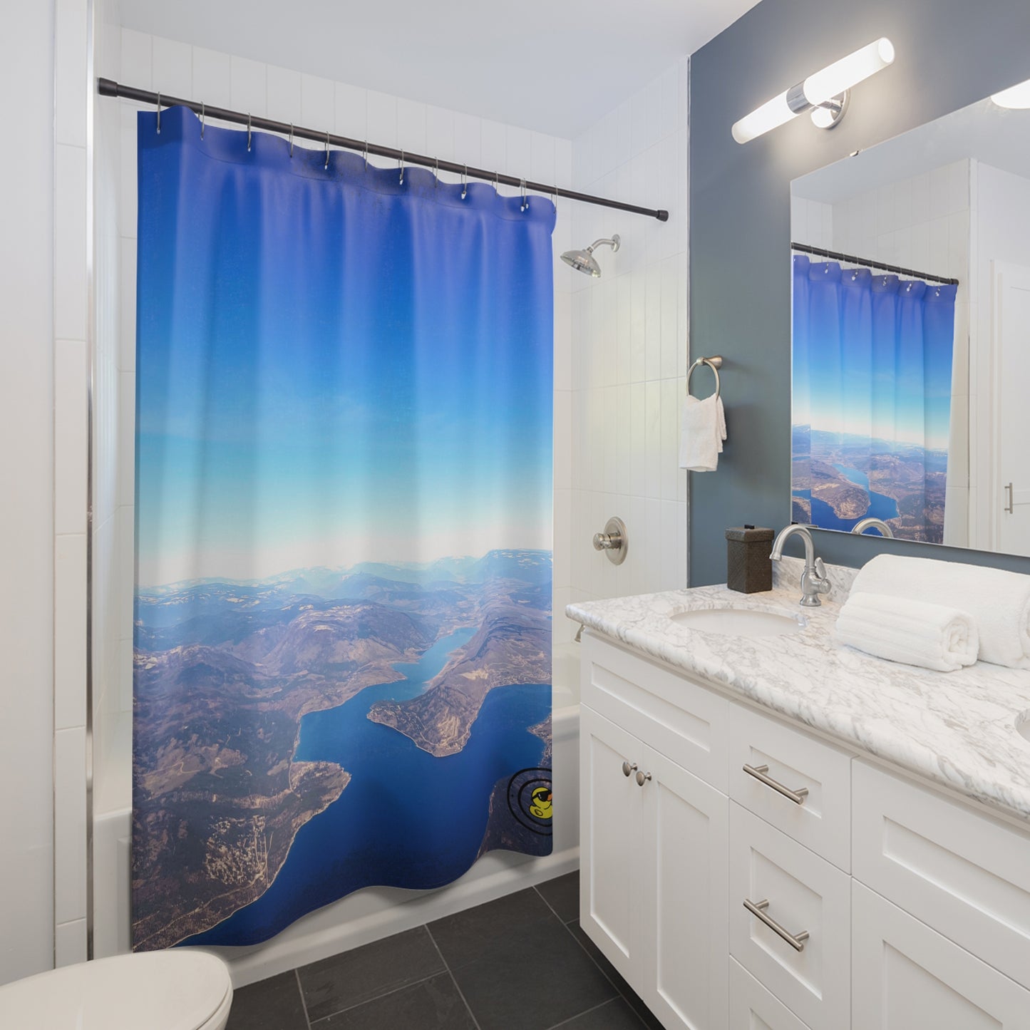 Contemporary bathroom with aerial view shower curtain, marble vanity, and wall-mounted mirror lighting.