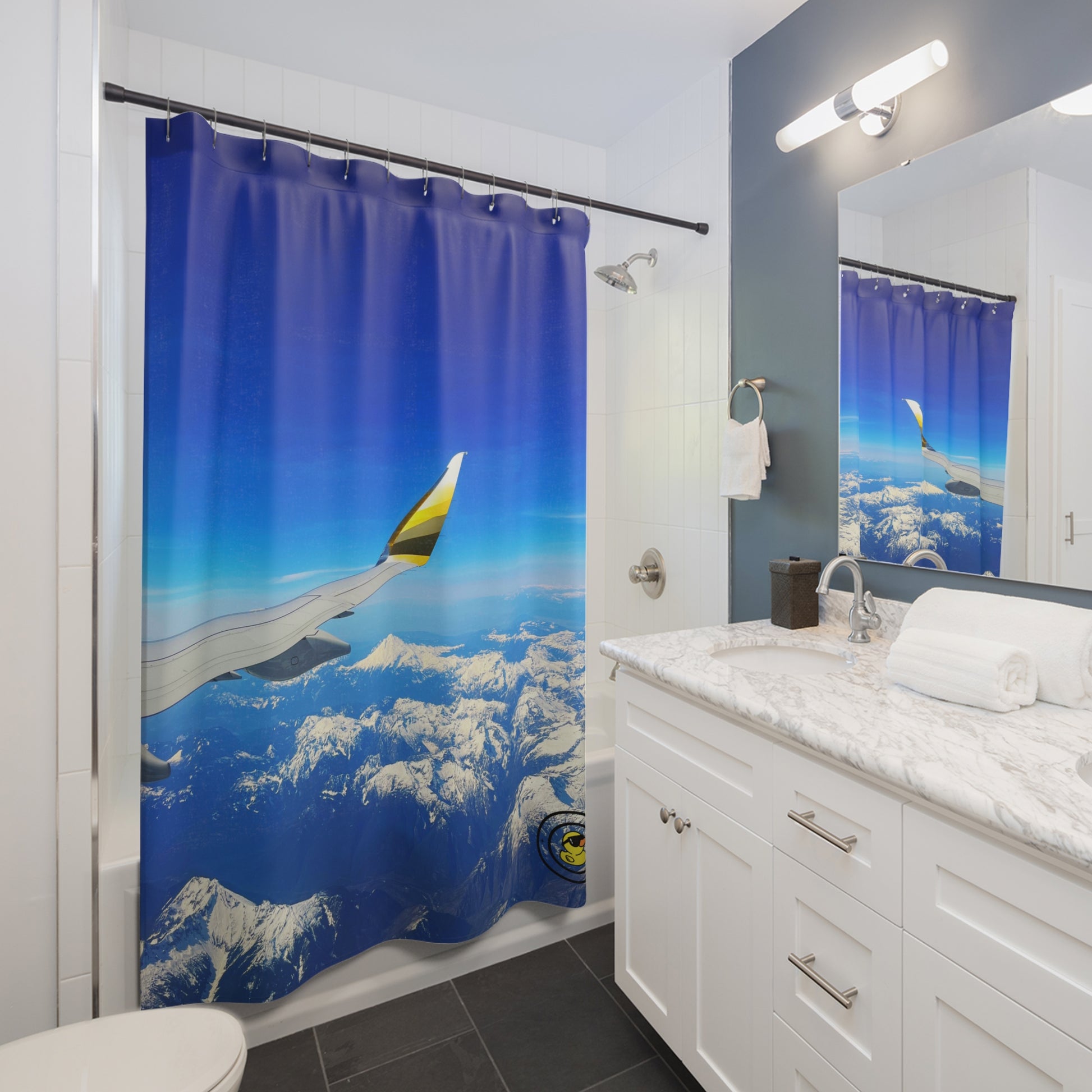 Shower curtain with airplane wing view over snowy mountain range in a sleek modern bathroom with mirror reflection.