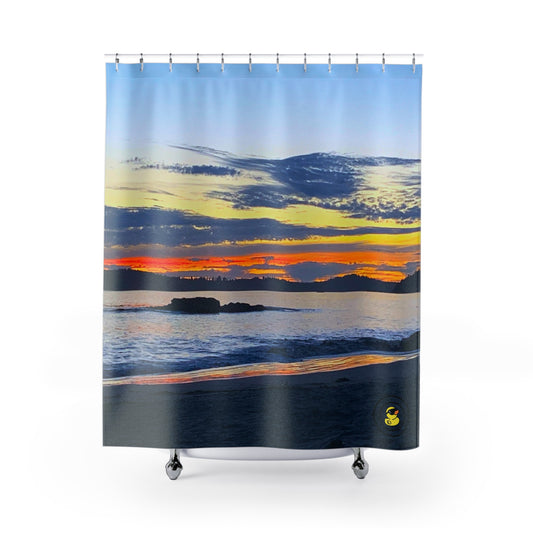 Shower curtain with a vivid island sunset, ocean waves, and silhouetted rocks under a colorful sky.